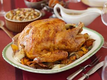 Apartments for rent in conroe A roasted turkey on a platter with herbs and vegetables on a red tablecloth, accompanied by a dish of stuffing and a gravy boat in the background.